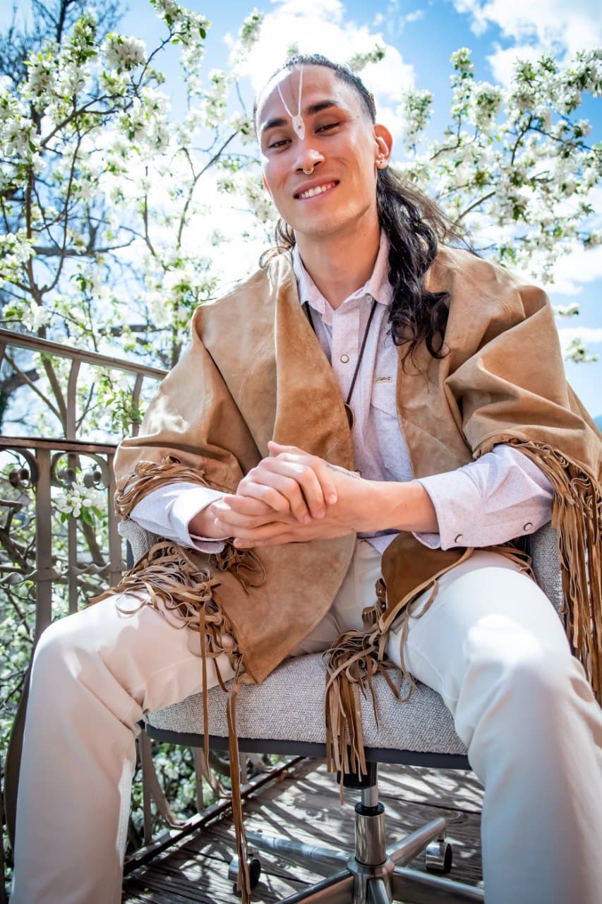 Connor “CBliss” Cunningham smiling on a balcony surrounded by blossoms